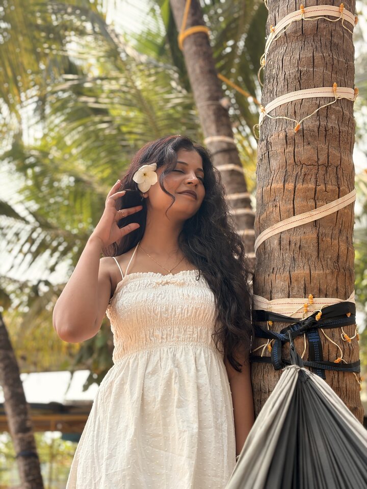 Sunlit white-dress portrait beside a hammock.