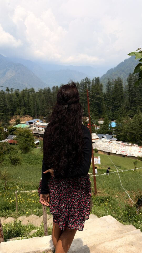Figure overlooking a green mountain valley.