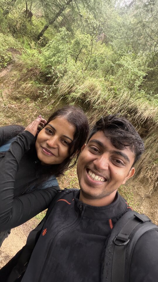 Smiling hiking selfie with greenery behind.