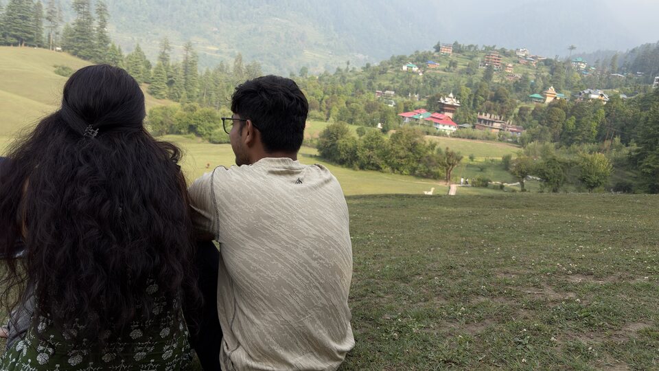 Two people seated facing a wide valley.
