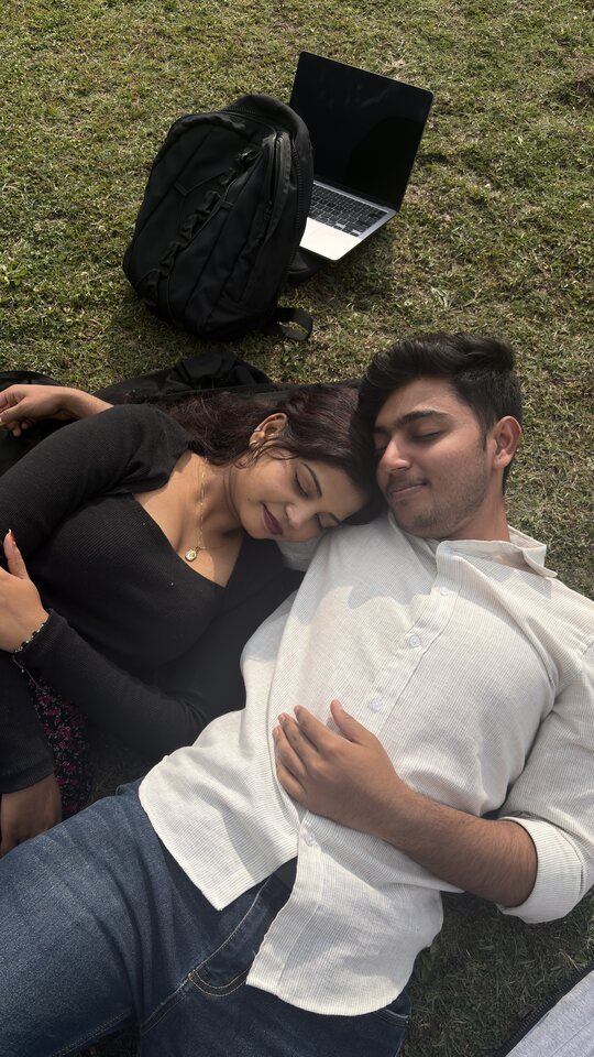 Couple resting together on the grass in sunlight.