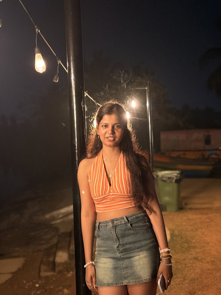 Woman standing beneath warm outdoor lights at night.