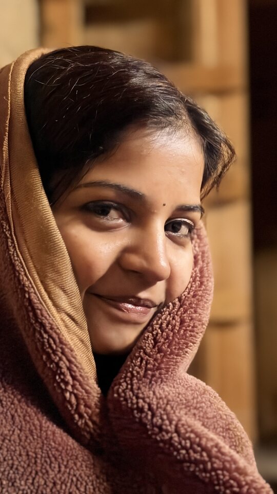 Warm close-up portrait wrapped in a soft blanket.