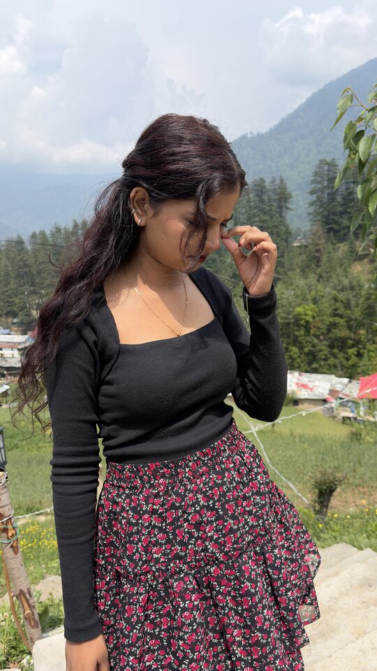 Woman in a floral skirt posing against a mountain valley.